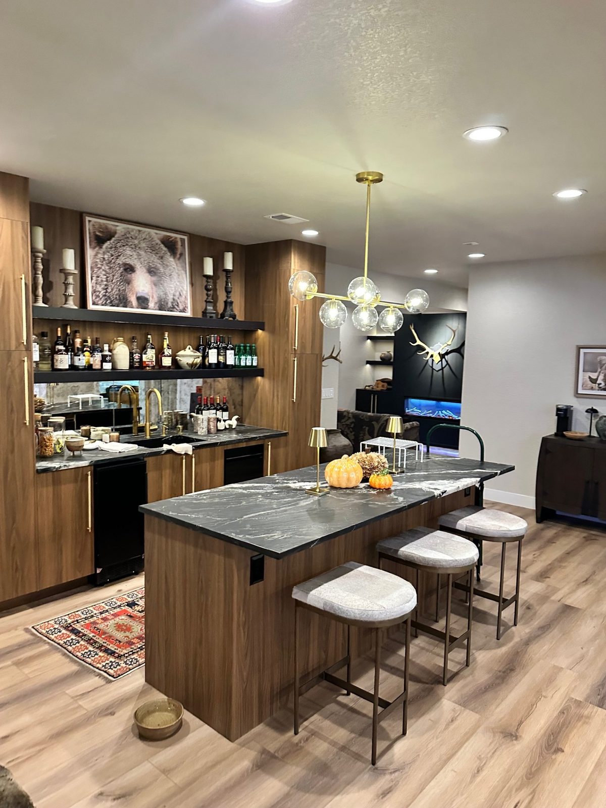 Custom finished basement with walnut wet bar, marble counters, and pendant lighting by Far West Construction in Fort Collins, CO