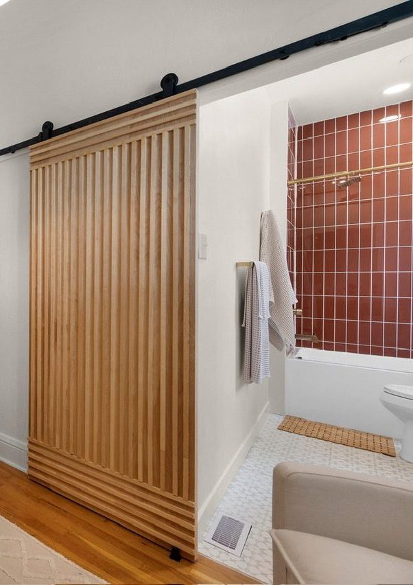Custom cedar slat barn door and en-suite bathroom with red tile shower by Far West Construction in Fort Collins, CO